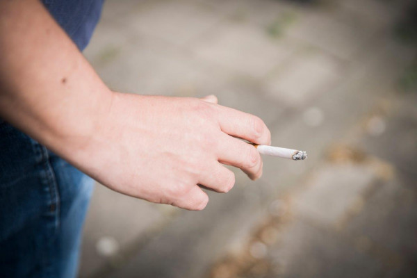 Hand met brandende sigaret van roker buiten